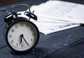 Black alarm clock with newspaper on a wooden table