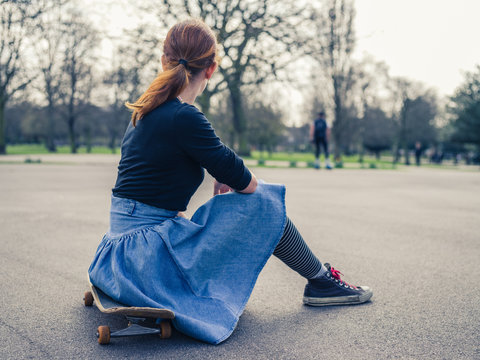 Woman sitting on a skateboard in the park
