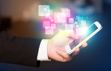 Hand holding smart phone with abstract glowing squares