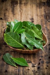 Fresh bay leaves in a wooden bowl on a wooden background