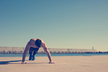 Young athlete with naked torso doing push-ups (intentional vinta