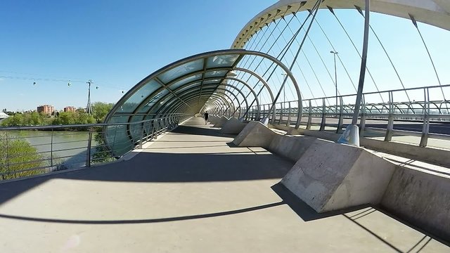 lenely pedestrian walking acros the futuristic bridge