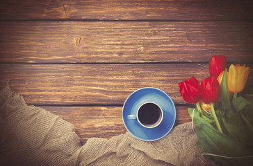 Cup of coffee with tulips near fabric