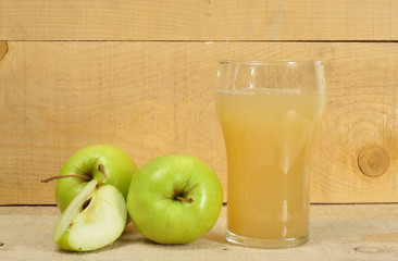 Apple juice and apples on wooden background