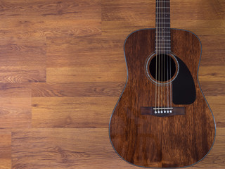Acoustic guitar leaning against the wooden wall