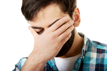 Young depressed man touching his face.