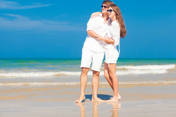 happy young couple in white clothes having fun on tropical beach