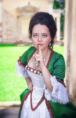 Beautiful woman in green medieval dress making silence gesture