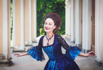 Beautiful young woman in blue medieval dress doing curtsey