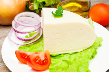soft goat cheese in a bowl on a wooden table with vegetables