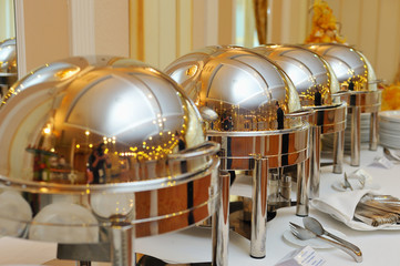 four closed stainless steel cloche on wooden table on restaurant