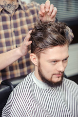 Obraz premium Barber makes hairstyling to a client