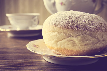 Macro shot of donut with cup of coffee on table in old-style