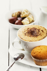 Hot cappuccino and pastries on white wooden boards