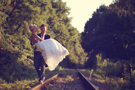 Groom carrying bride on railroad