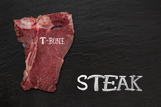 Raw beef t-bone steak on black stone