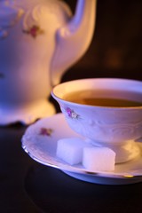 Old-style kettle with cup of tea on black