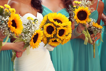 Bride and bridesmaid holding beautiful sunflower bouquet
