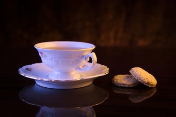 Old-style image cup of tea with cookies on black