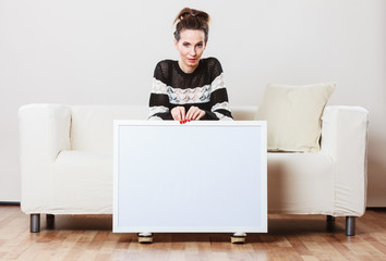 woman on sofa holding blank presentation board.