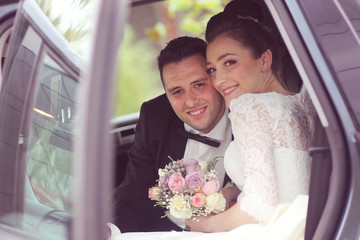 Bride and groom posing in car
