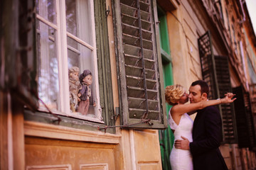 Bridal couple holding each other next to vintage window