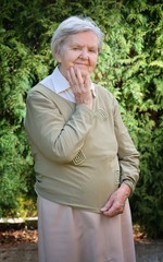 Senior woman smiling and dreaming in garden.