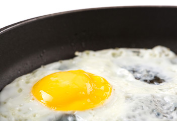 Fried egg in a frying pan over white background