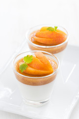 dessert with cream and apricot jelly in glasses on white plate