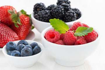 Fresh berries in bowls on a white wooden table, close-up