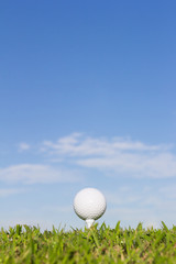 Golf ball on tee with sky background