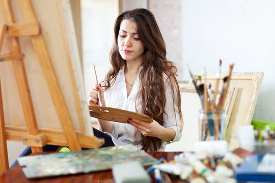 Long-haired female artist paints picture