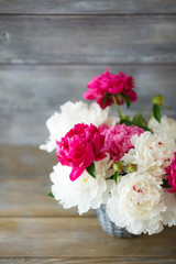 Peonies in a wicker vase on the boards