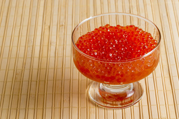 bowl with red caviar on a bamboo napkin closeup