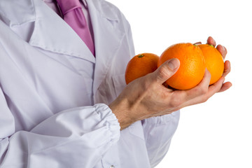 man in medical white coat showing 3 oranges