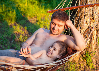 Father dad tickling kid daughter child in hammock