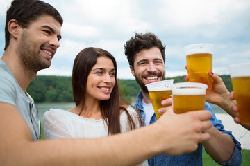Vier Freunde mit Plastikbechern stoßen gemeisam an