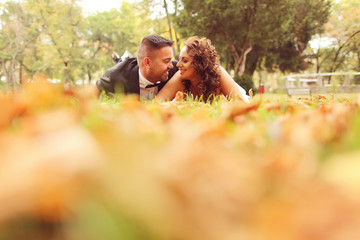 Fototapeta premium Bride and groom laying on autumn leaves