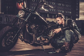 Biker repairing his custom motorcycle bobber on a road © Nejron Photo