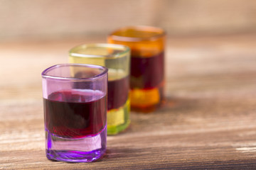 Filled coloured glasses on wooden background