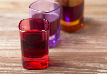 Filled coloured glasses on wooden background