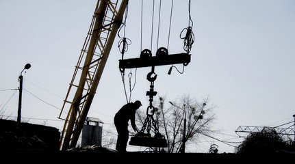 Mechanic adjusts magnetic crane at junkyard