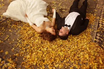 Bride and groom laying on autumn leaves