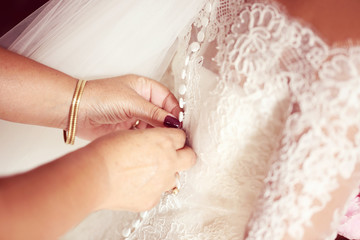 Fototapeta premium Hands helping the bride with wedding dress