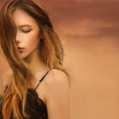 portrait of a beautiful dreamy girl on a background of red sky