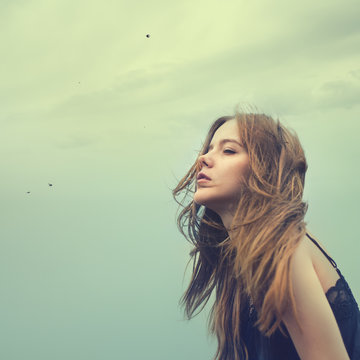 beautiful young girl in a windy day against the sky