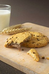 Chocolate chip cookies on a wooden board with milk