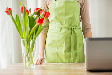 close up of woman with tulips in vase and laptop