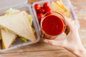 close up of woman hand holding tomato juice glass