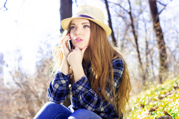 Beautiful young blonde in a hat with a phone